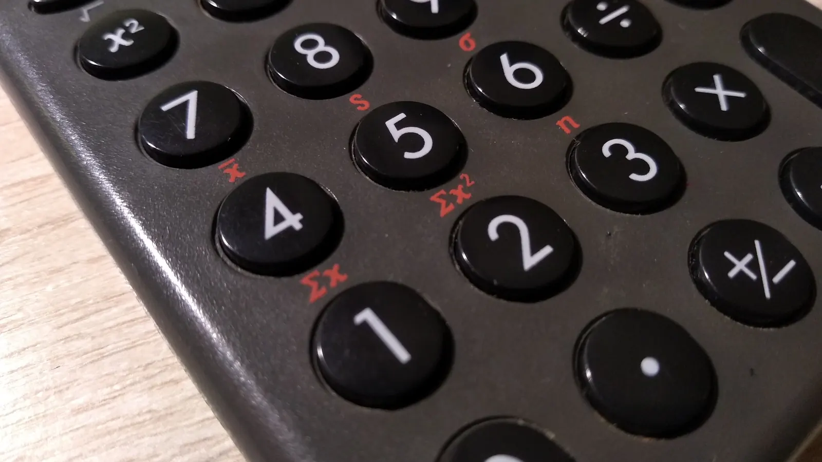 A close-up of a black calculator keypad with white digits, shot at a slight angle